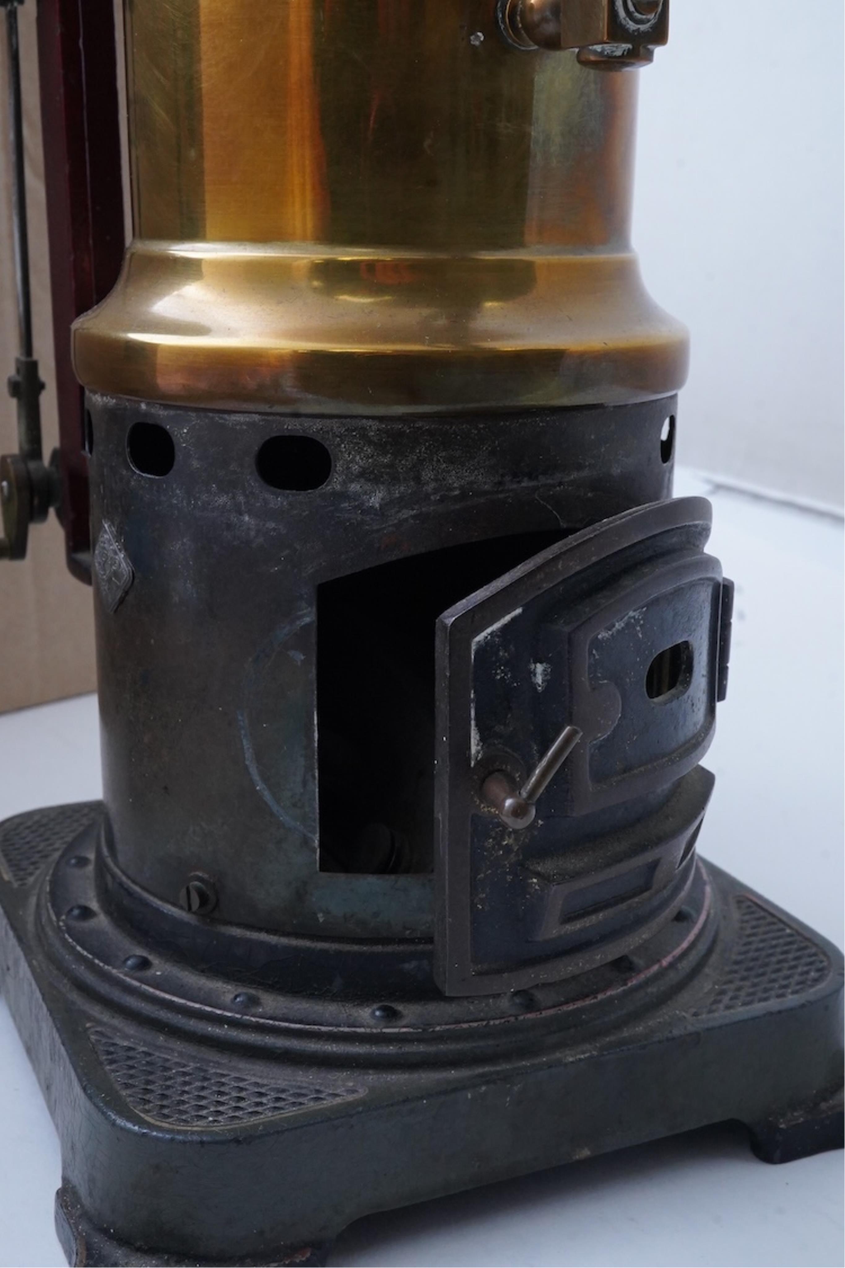 An early 20th century Bing live steam single cylinder vertical stationary engine, of brass, tinplate and cast iron construction, 38cm high, 10.5cm diameter flywheel, complete with the burner, together with a steam plant